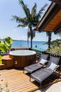 eine Terrasse mit 2 Stühlen und einer Badewanne in der Unterkunft Casa Vista Mar com Ofurô - Condomínio com piscina in Bombinhas + 12 Fotos