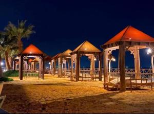 Una hilera de cenadores en la playa por la noche en Chalet Blumar eldom elsokhna, en Ain Sokhna