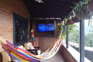 a hammock on a porch with a tv at Pedacito de cielo in San Antonio de Prado