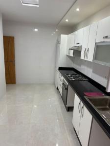 a kitchen with white cabinets and a black counter top at Apartamento Nador AlJadid 2 in Nador +9 photos