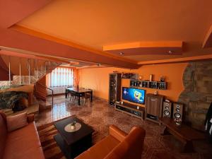a living room with a couch and a tv and a table at La Conac Complex Deluxe Targu-Jiu in Târgu Jiu