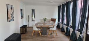 a dining room with a table and white chairs at Appartement de 65m2 avec piscine partagée in Tremblay-En-France