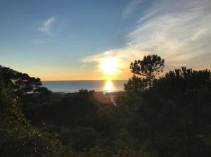 una puesta de sol sobre el océano con el sol en el cielo en Surf Camp Ecológico, en Costa da Caparica