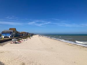 a beach with a group of people and the ocean at Maison 4-8 personnes, jardin, Sainte Mère Eglise in Sainte-Mère-Église