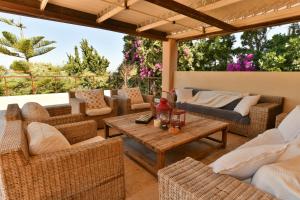 a patio with wicker furniture and a wooden table at Sunset Villa in Saronida