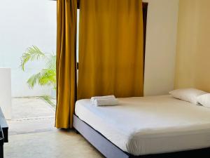 a bed in a room with a yellow curtain at Casa Coral Pueblito - Self Check In in Mahahual