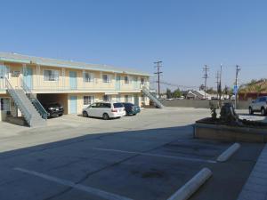 a large building with cars parked in a parking lot at Western Inn & Suites in Taft