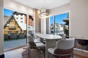 a dining room with a table and chairs and a large window at Tribeca 2 Suítes 350m Rua Coberta by Achei Gramado in Gramado