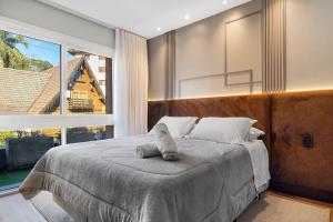 a bedroom with a large bed and a large window at Tribeca 2 Suítes 350m Rua Coberta by Achei Gramado in Gramado