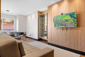 a living room with a couch and a tv on a wall at Tribeca 2 Suítes 350m Rua Coberta by Achei Gramado in Gramado