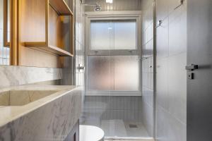 a bathroom with a shower and a toilet and a window at Tribeca 2 Suítes 350m Rua Coberta by Achei Gramado in Gramado +27 photos