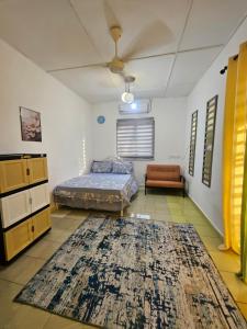a bedroom with a bed and a couch and a rug at Homestay Sarah Ali Kuantan 3BEDROOM 2WASHROOM SELESA,BERSIH & LUAS in Kuantan