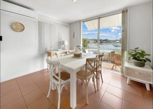una sala da pranzo con tavolo, sedie e una finestra di Mooloolaba Waterfront Two Story Unit with Pontoon a Mooloolaba