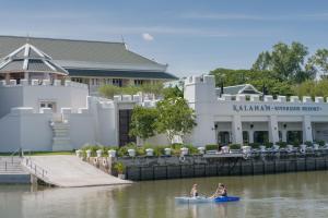 two people in a kayak in the water in front of a building at Kalanan Riverside Resort in Nonthaburi