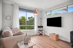 Una sala de estar con un sofá y un televisor de pantalla plana. en 60A Mentone Road, Hayborough, en Hayborough