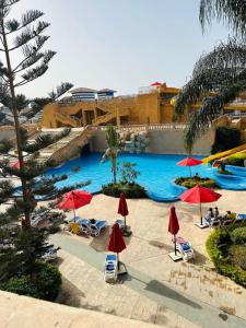 エル・アラメインにあるشقه فندقية بورت ماريناのリゾート内の赤いパラソルと椅子のあるプール