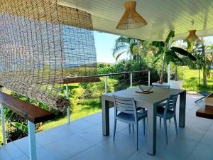 a porch with a table and chairs on a balcony at Fare Outu Iti in Punaauia