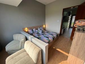 a bedroom with a bed and two chairs in it at Villa makota kota batu in Batu
