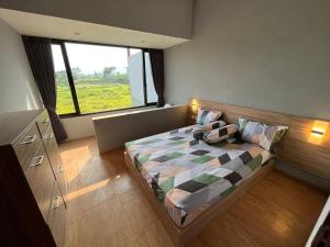 a bedroom with a bed with a large window at Villa makota kota batu in Batu