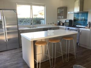 Una cocina con una gran isla blanca con dos taburetes de bar. en Wanaka Holiday, en Wanaka
