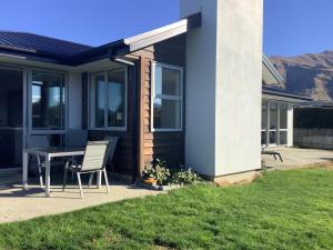 un patio con una mesa y una silla frente a una casa en Wanaka Holiday, en Wanaka