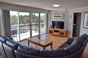 Una sala de estar con un sofá de cuero y un televisor. en Ocean Shores Apartment 15 - Bring your own linen., en South West Rocks 4 fotos más