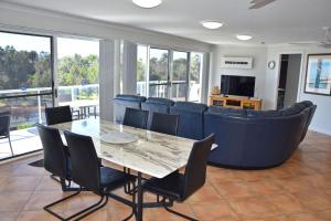 Un comedor con una mesa y sillas y un sofá. en Ocean Shores Apartment 15 - Bring your own linen., en South West Rocks