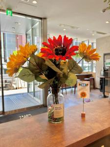 a vase filled with flowers sitting on a table at ICI HOTEL Ueno Shin Okachimachi in Tokyo