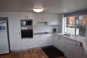 Una cocina blanca con gabinetes blancos y una ventana. en Ocean Shores Apartment 14 - Bring your own linen., en South West Rocks