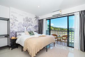a bedroom with a bed and a large window at Mitsu Guesthouse in Karon Beach