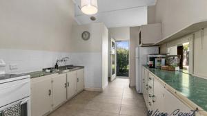 a kitchen with white cabinets and a clock on the wall at Vintage Vista By Wine Coast Holidays in Port Willunga