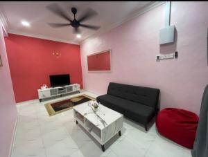 a living room with a black couch and a red wall at Ammaiti Homestay Kulim in Kulim