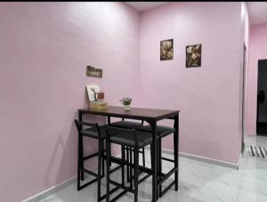 a table in a room with a pink wall at Ammaiti Homestay Kulim in Kulim