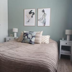 a bedroom with a bed with three pictures on the wall at Saunallinen viihtyisä kaksio keskustan tuntumassa in Kouvola