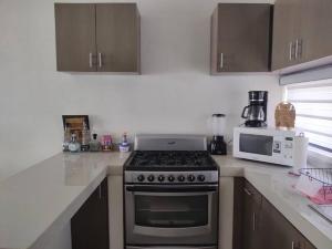 a kitchen with a stove and a microwave at Bonita casa amueblada in Colima