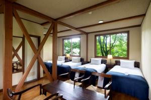 a room with four beds and a table and chairs at Hotel Wohnen in Hakuba