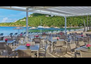 a restaurant with tables and chairs on a beach at Beach fun with the family in this resort 3BD with onsite activities pool, kids room, and more in Cruz Bay
