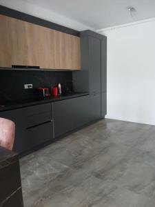 eine Küche mit schwarzen Schränken und Betonboden in der Unterkunft Apartament Wave5 in Năvodari + 6 Fotos