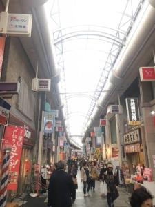 東京にある椿Salon 十条の商店街を歩く人々