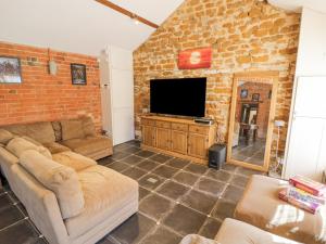 a living room with a couch and a tv at Hill House Farm in Northampton