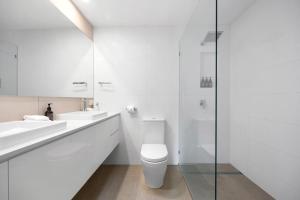 a white bathroom with a toilet and two sinks at Moondarah: Pet-Friendly Escape in Noosa Heads +5 photos