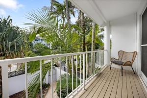 a balcony with a chair and palm trees at Moondarah: Pet-Friendly Escape in Noosa Heads