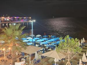 a group of umbrellas and chairs on the beach at night at Durres Sun & Sea Luxury Apartment in Durrës