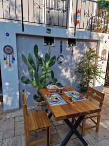 a table and chairs in front of a wall with a cactus at OTELIA PANSIYON in Ayvalık