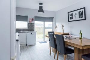 a kitchen and dining room with a wooden table and chairs at Bunhovil -3 bedroom in Bundoran
