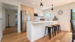 Una cocina con barra con taburetes y refrigerador. en Classic 70's Beach House Outside - 97-99 Lohr Avenue, en Inverloch