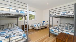 1 dormitorio con 3 literas y mesa en Classic 70's Beach House Outside - 97-99 Lohr Avenue, en Inverloch