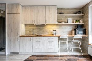 a kitchen with white cabinets and white stools at Park's Edge apartment in Kaunas