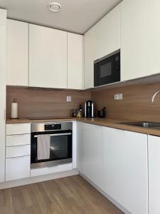 eine Küche mit weißen Schränken und einer Mikrowelle in der Unterkunft Tyylikäs saunallinen huoneisto Sotkamon satamassa in Sotkamo