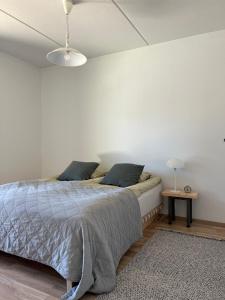 ein Schlafzimmer mit einem Bett und einer weißen Wand in der Unterkunft Tyylikäs saunallinen huoneisto Sotkamon satamassa in Sotkamo